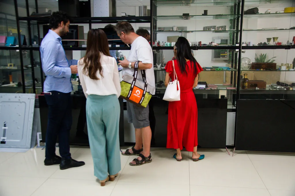 A host and overseas visitors examining moulded products in a Shenzhen factory showroom